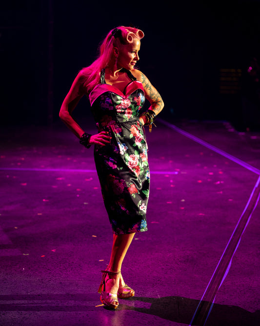 Pinup model Judy walking for Hollyville in the Viva Las Vegas Rockabilly Weekend Fashion Show wearing a pink floral stretch satin wiggle dress. Photo by Craig Maxfield