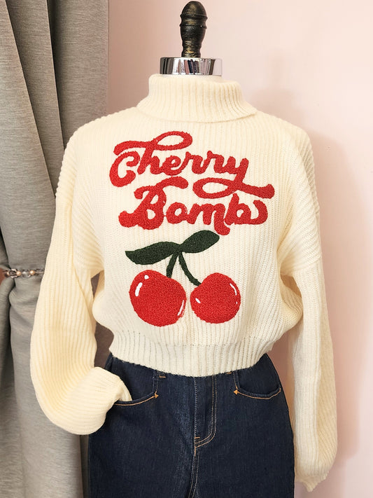Vintage inspired cherry crop sweater displayed on a mannequin against a pink wall at Hollyville pinup boutique in South Milwaukee.