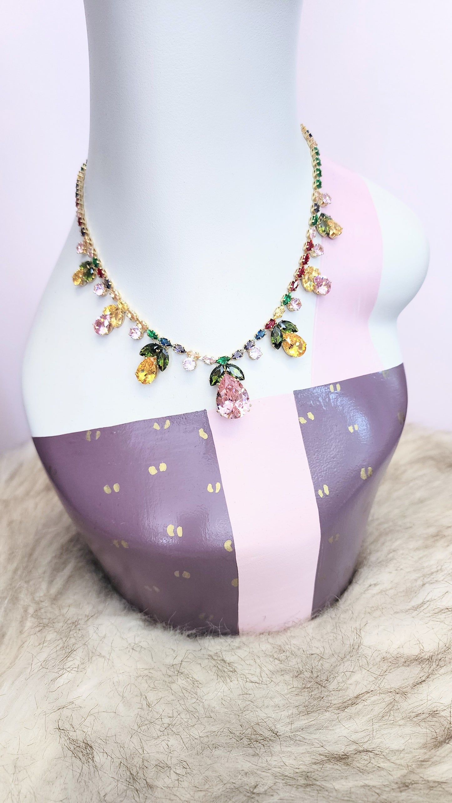 Necklace with pastel rhinestones on a mannequin bust against a pink background