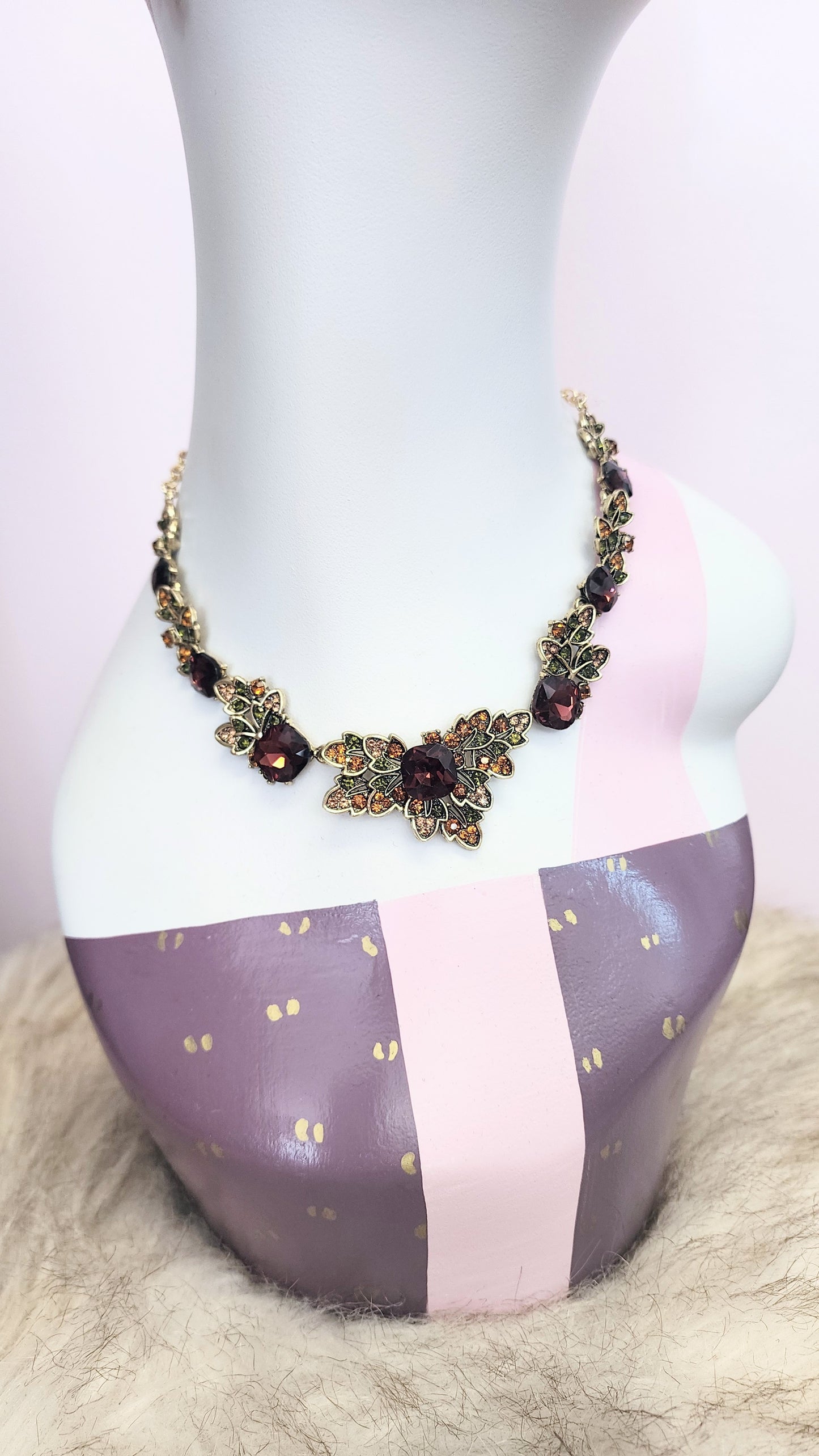 Necklace with dark crystals and gold accents displayed on a mannequin bust at Hollyville in South Milwaukee
