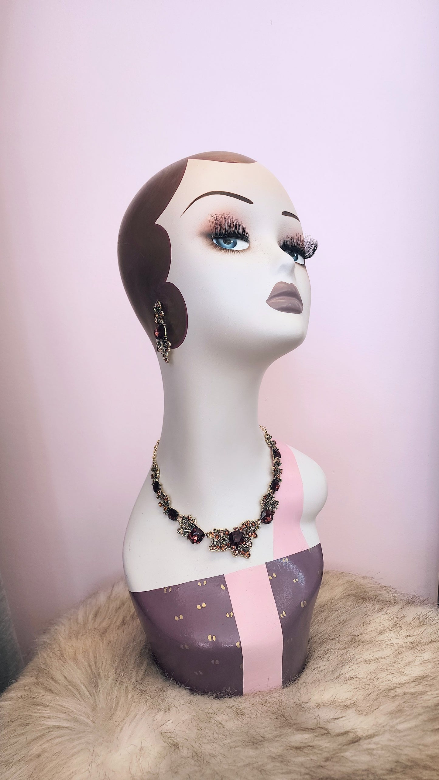 Mannequin head with leaf crystal necklace and earrings on a pink background at Hollyville Pinup Boutique in South Milwaukee.